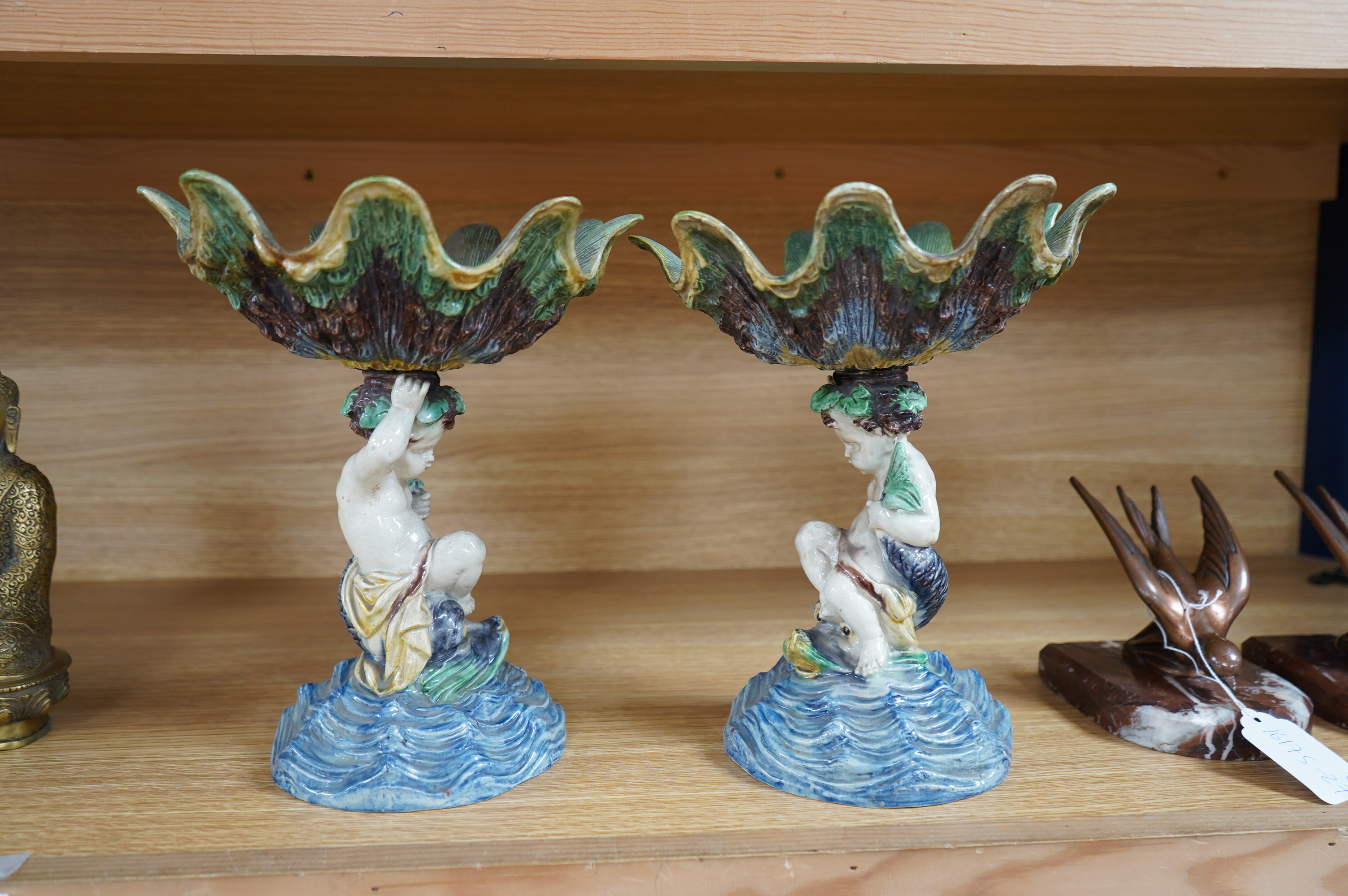 A pair of 19th century majolica comports with putti stems, 25cm. Condition - one repaired